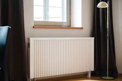 Radiateur blanc sous une fenêtre dans une pièce lumineuse.