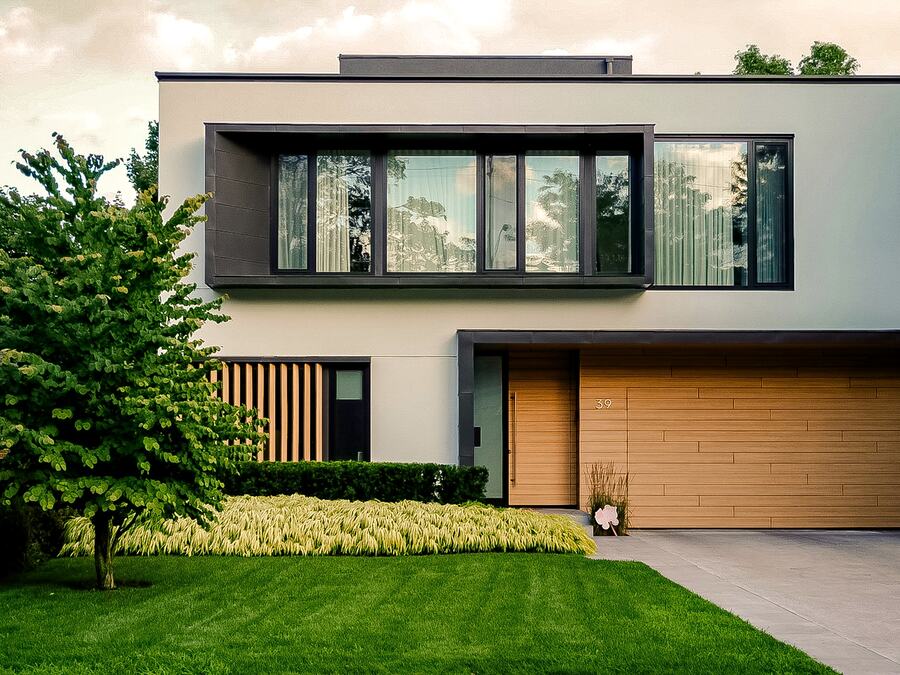 Façade d'une maison individuelle contemporaine, bardage bois et enduit clair, un jour de lumière naturelle.