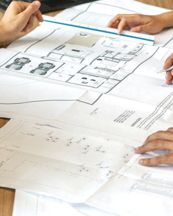 Étude d'un projet de rénovation : plans dépliés, règle et notes sur une table de travail.